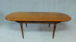 A Continental flame mahogany extending dining table with brass mounts and central floral inlay