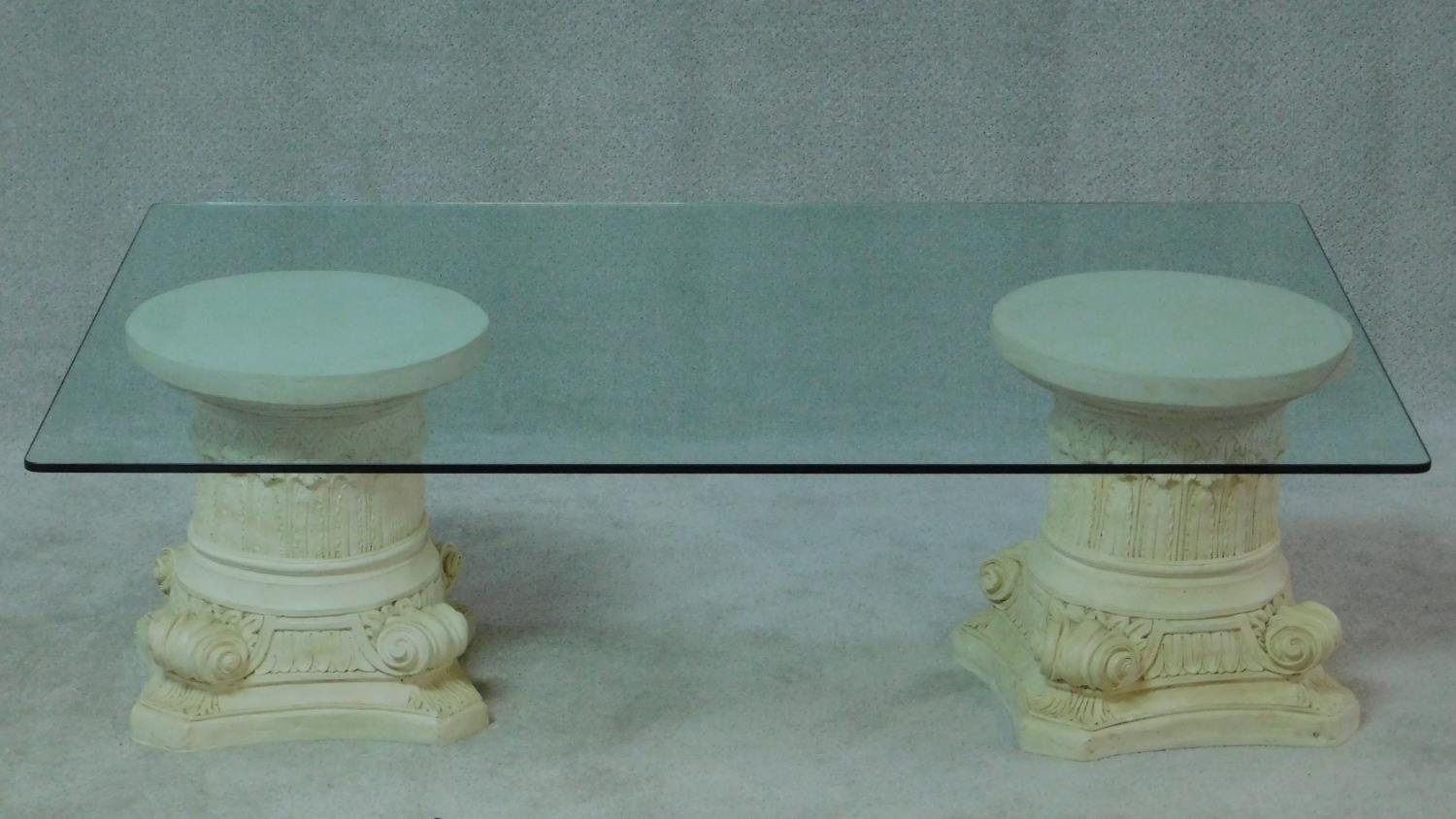 A plate glass low coffee table on inverted Corinthian capital supports. H.40 W.130 D.90cm