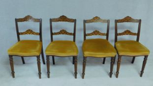 A set of four late Victorian beech dining chairs with profusely floral inlaid back rails on tapering