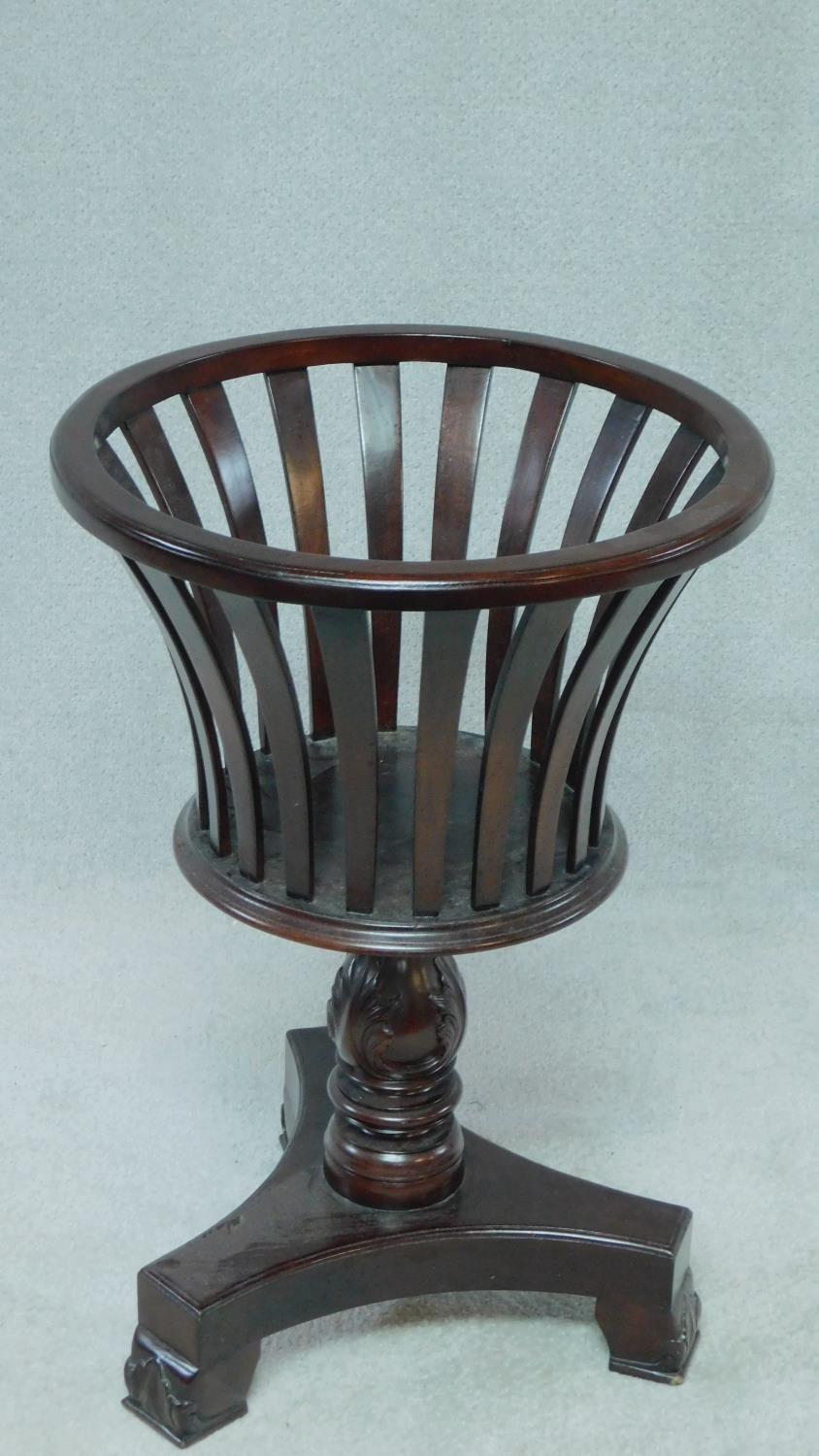 A 19th century style teak jardiniere stand with shaped slatted sides on carved tripod platform base.