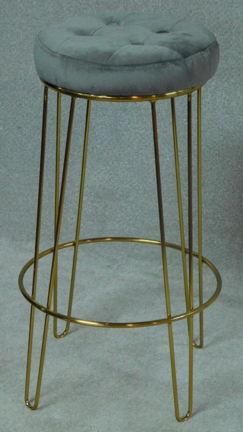 A vintage style cocktail stool in petrol blue buttoned upholstery on gilt metal hairpin supports.