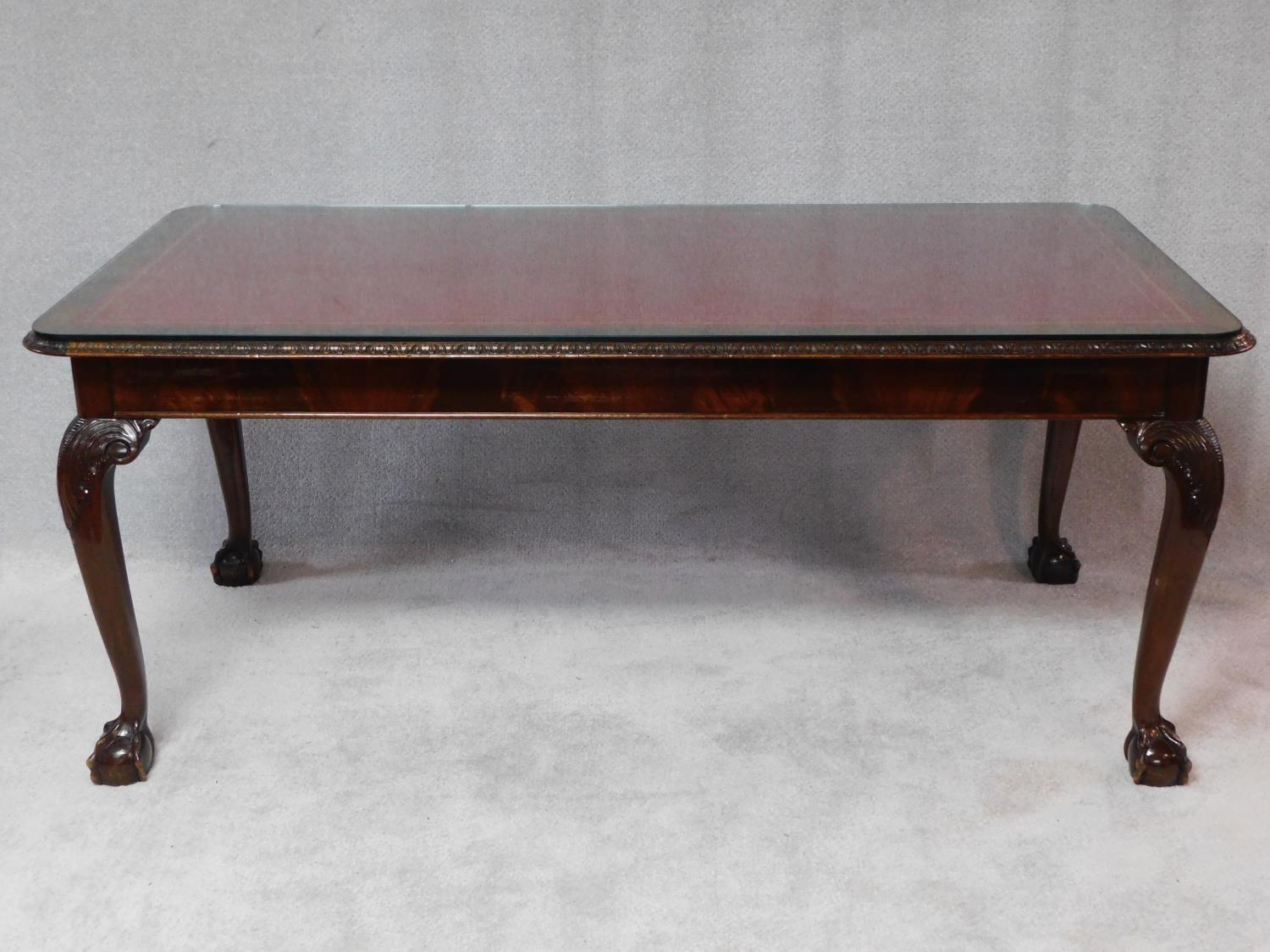 A mid Georgian style mahogany library table with inset tooled leather top on carved cabriole