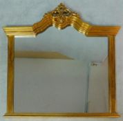 A gilt framed overmantel mirror with scrolling architectural pediment the plate flanked by pilasters