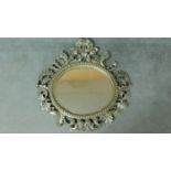 A circular wall mirror in scrolling floral silvered frame. 97x100cm
