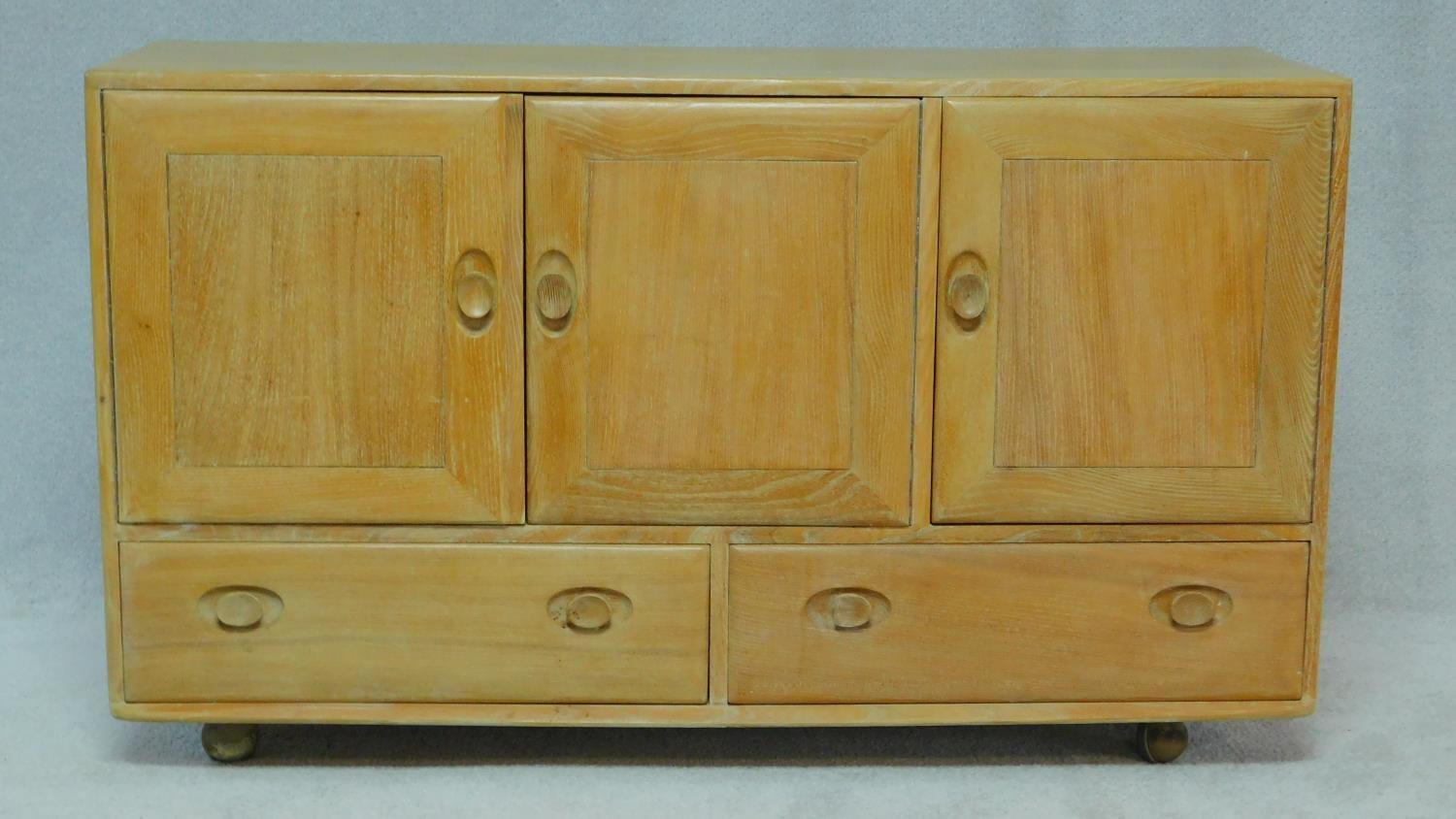 A vintage blonde elm Ercol sideboard, model 468, with an arrangement of drawers and cupboards raised