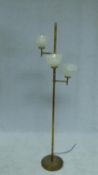 A vintage floor standing brass lamp standard with three branches fitted with opaque glass