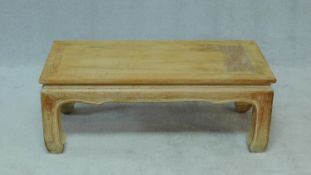 A Burmese teak low coffee table with carved and shaped frieze on bowed block supports. H.42 W.107