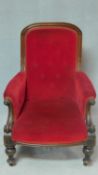 A Victorian mahogany framed armchair in buttoned upholstery on turned tapering supports. H.103 W.