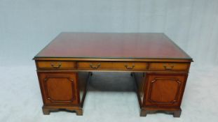 An Georgian style mahogany partner's desk with plate glass top resting on tooled leather inset above