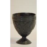 An antique carved coconut chalice, carved with four cartouches, two with tropical flowers, an anchor