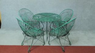 A green painted vintage style metal garden table together with four matching chairs with scroll