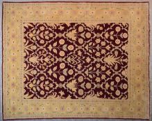 A Moghul design carpet with repeating floral lozenge motifs on a vermillion ground contained