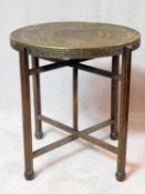 A 19th century Islamic brass top foldable table with repousse calligraphy decoration and four legged