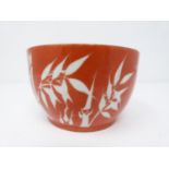 A small Chinese rice bowl with bamboo and calligraphy decoration on a deep red ground, character