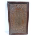 A 19th century framed Islamic repoussé copper plaque with calligraphy design and scrolling motif