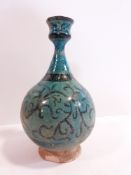 An Islamic Kashan turquoise glazed bottle vase decorated with a black scrolling foliate design with