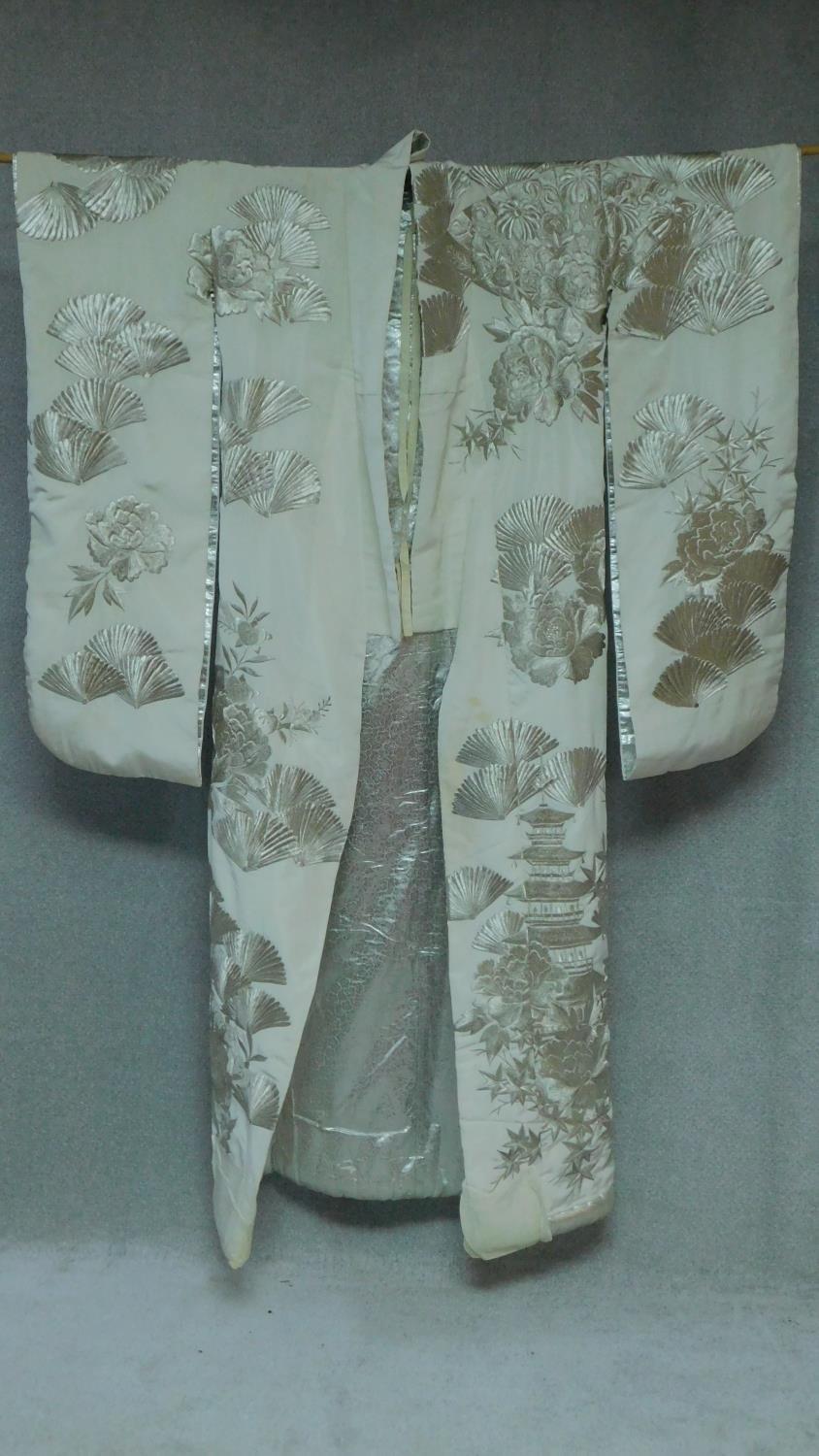 A Japanese cream silk metallic embroidered kimono, decorated with flowers, fans and pagodas.
