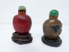 Two Qing dynasty carved snuff bottles. One made from orange/red dappled realgar glass with a jade
