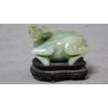 A 20th century Chinese carved serpentine jade water buffalo on a footed pierced carved hardwood