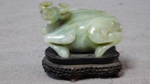 A 20th century Chinese carved serpentine jade water buffalo on a footed pierced carved hardwood