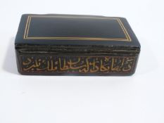 A 19th century Qajar lacquer snuff box decorated with calligraphy and a linear border to the top.