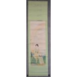 A Japanese mounted scroll, watercolour on paper, lady seated in a garden holding a book, signed with