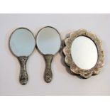 Three Turkish silver and white metal mirrors with repousse design. One with a scalloped edge and