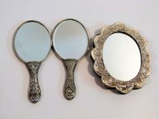 Three Turkish silver and white metal mirrors with repousse design. One with a scalloped edge and