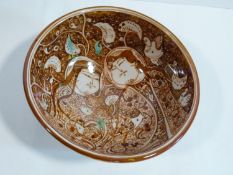 A Persian glazed ceramic lustre bowl decorated with a lovers and foliage and calligraphy around