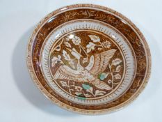A Persian glazed ceramic lustre bowl decorated with a woodpecker among foliage and calligraphy