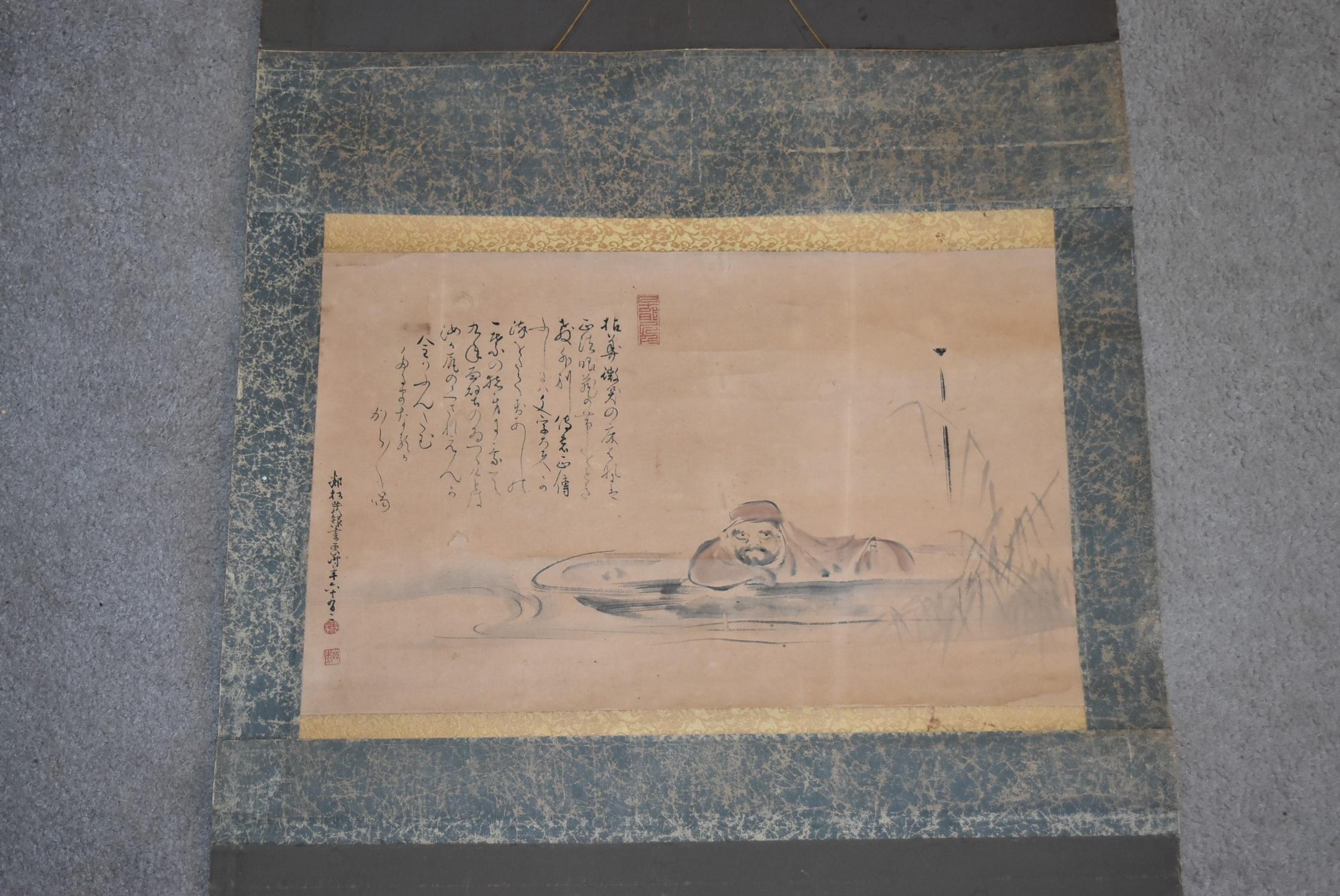 A Japanese mounted scroll, ink on paper, a man lying low in a punt in floral textile borders, - Image 4 of 4