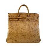 A gold Hermes Birkin Haut à Courroies (HAC) in ostrich leather with gold hardware, includes brown