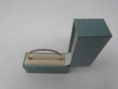 A boxed 9ct yellow and white gold diamond set bangle with hook fastening. Set with fifteen round