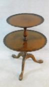 A Georgian style burr walnut two tier dumb waiter with carved piecrust edges raised on tripod