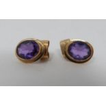 A pair of oval 18 carat yellow gold and amethyst stud earrings. Each set with an oval mixed cut