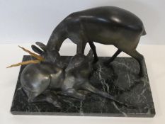 A pair of spelter Art Deco male and female gazelles mounted on a black and white veined marble base.