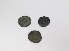 Three ancient bronze coins. One with profile of an Emperor with wreath around his head one side