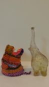 A multicoloured wall mounted lions head made from striped rope along with a glass bottle in the form