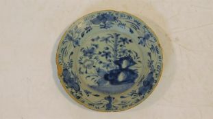 An antique blue and white floral design glazed hand painted ceramic plate. It has a bright yellow