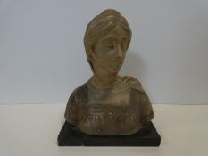An antique carved alabaster bust of a woman in a head scarf and pleated neck dress. Mounted on a
