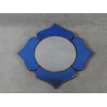 An Art Deco circular wall mirror set within a quatrefoil blue glass frame. H.55xW.55cm