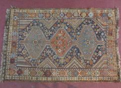 A Kashkai rug with triple pole medallions on midnight ground contained within burgundy stylised