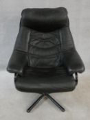 A vintage black leather upholstered reclining armchair with swivel action on metal five point