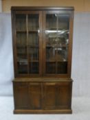 A mid century oak library bookcase with upper glazed section enclosing bookshelves above base fitted