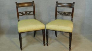 A pair of late Georgian mahogany dining chairs with carved backs above stuffover seats on turned