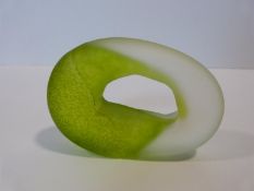 An Art Glass green and clear pierced doughnut paperweight of amorphous form. Indistinct signature to