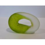 An Art Glass green and clear pierced doughnut paperweight of amorphous form. Indistinct signature to