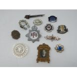 A collection of twelve antique brooches and badges. Including a carved mother of pearl brooch with