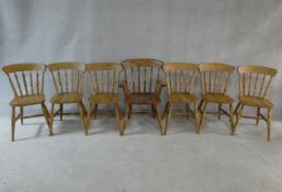 A set of seven spindle back kitchen dining chairs with rail backs on turned stretchered supports,