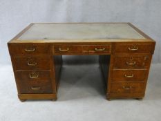 A mid century oak pedestal desk with inset leather top above an arrangement of nine drawers. H.